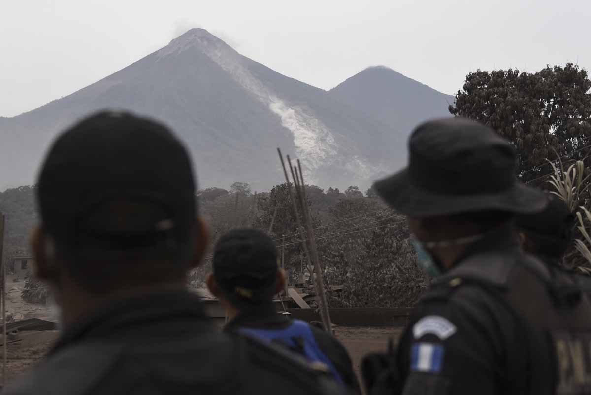 Police officers look at the Fuego Volcano from San Miguel Los Lotes, a village in Escuintla Department, about 35 km southwest of Guatemala City, on June 4, 2018, a day after an eruption. At least 25 people were killed, according to the National Coordinat