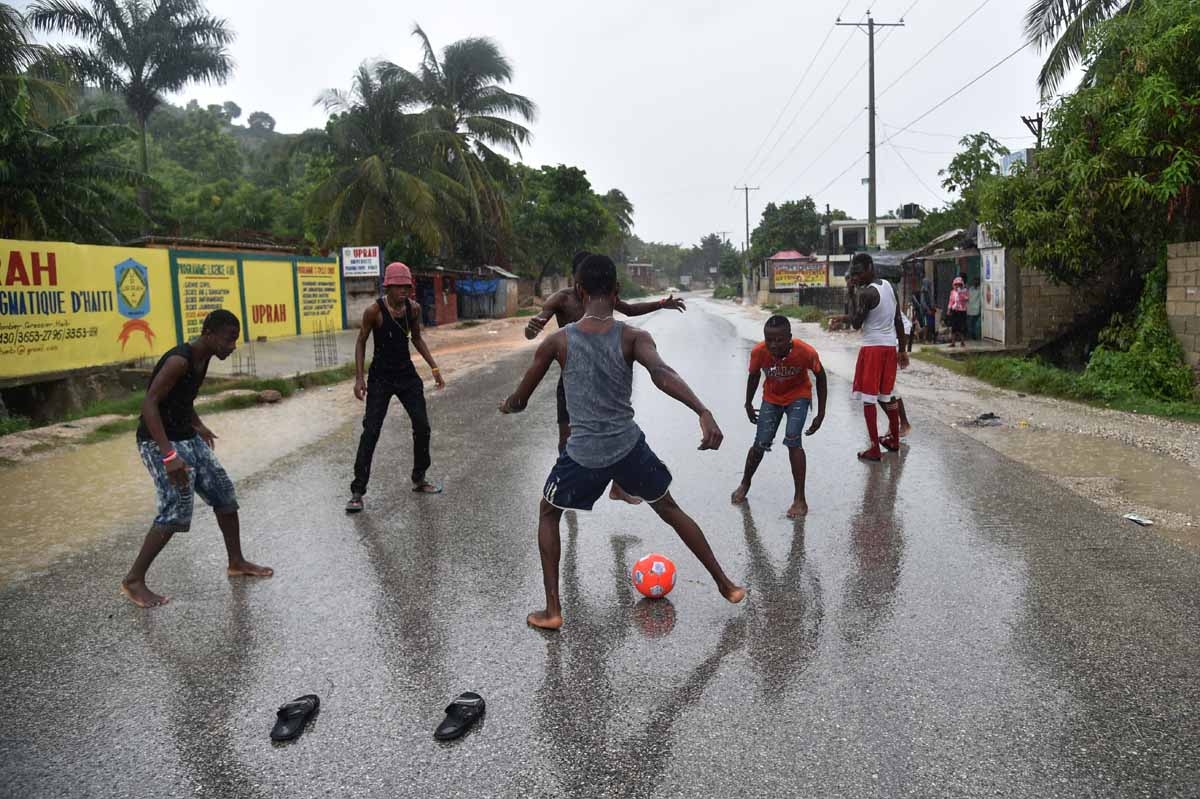 A group of young men play football in the rain on the route to Leogane, during the passing of the Hurricane Matthew, in Grassier, southwest of Port-au-Prince, on October 4, 2016. A group of young men play football in the rain on the route to Leogane, during the passing of the Hurricane Matthew, in Grassier, southwest of Port-au-Prince, on October 4, 2016.