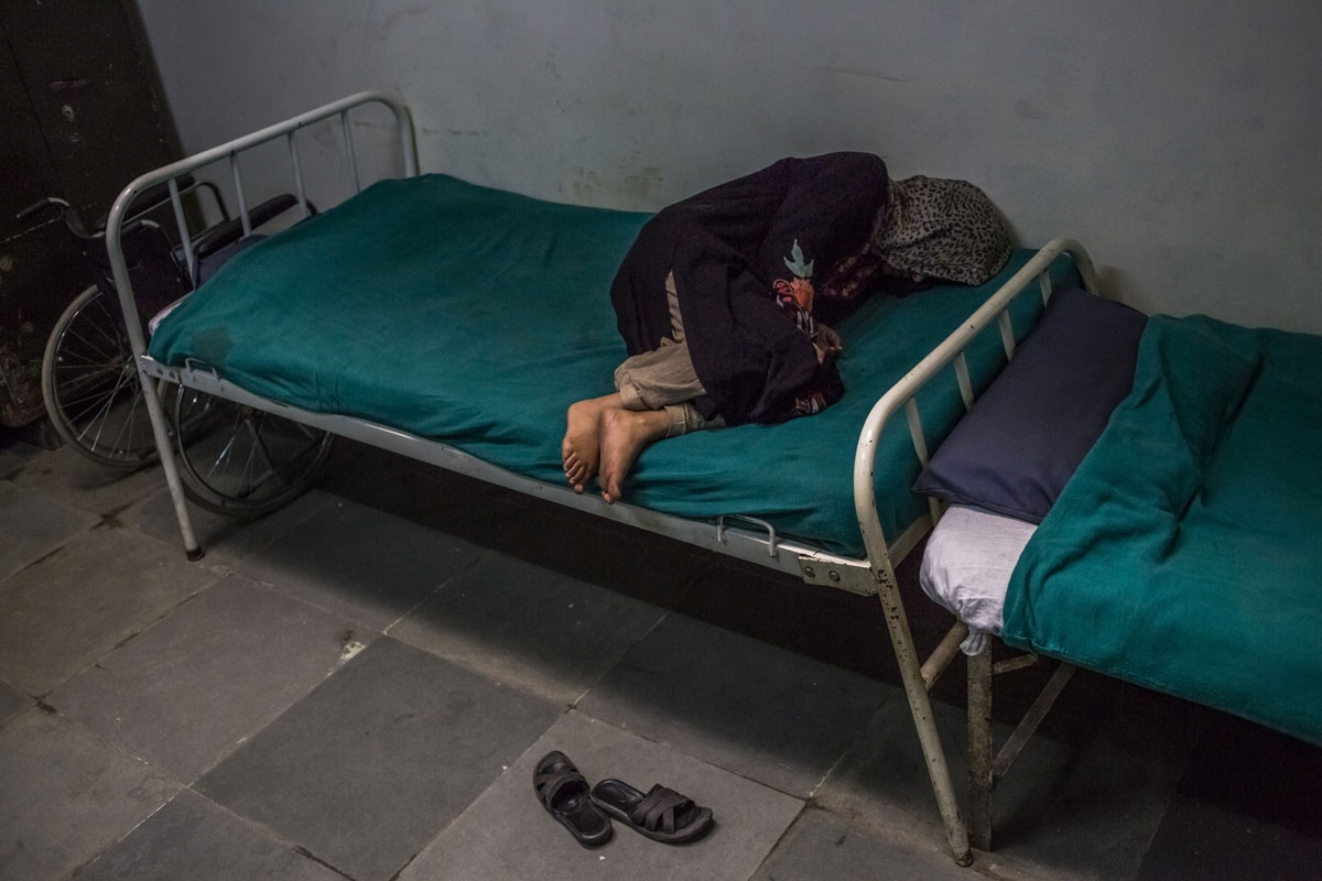 In this photo taken on November 20, 2015, Kashmiri patient Masrat Naz, 45, and who is suffering from symptoms of schizophrenia, lies on a bed as she periodically shouts to medical staff after being brought by relatives to the casualty ward at the Psychiat