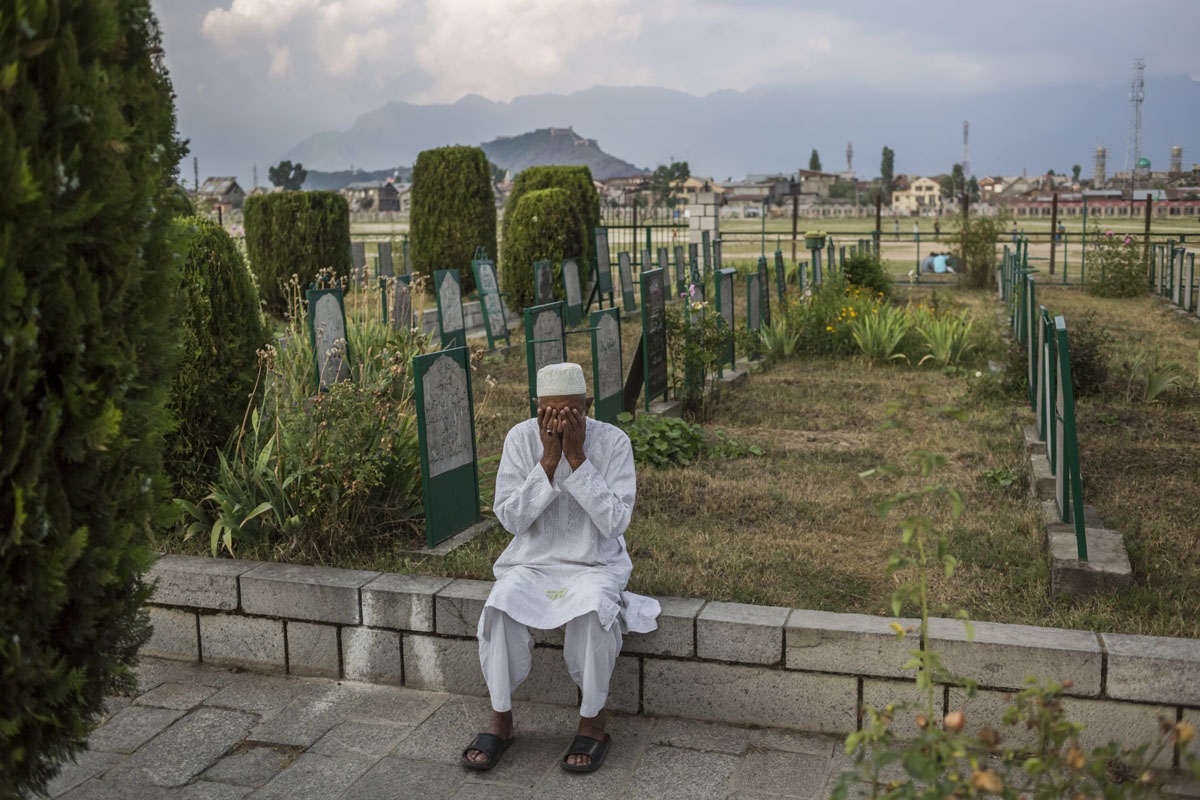In this photo taken on June 11, 2016, Kashmiri resident Hamidullah Khan, 65, wipes his hands over his face after singing a prayer at the Martyrs' Graveyard in the Eidgagh area of downtown Srinagar. Khan lives in Eidgagh and comes to the graveyard almost e