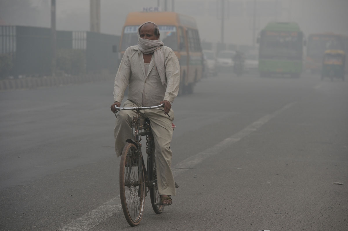 A cyclist covers his face while riding along a major road as smog covers the capital's skyline in New Delhi on November 2, 2016. A cyclist covers his face while riding along a major road as smog covers the capital's skyline in New Delhi on November 2, 2016.
