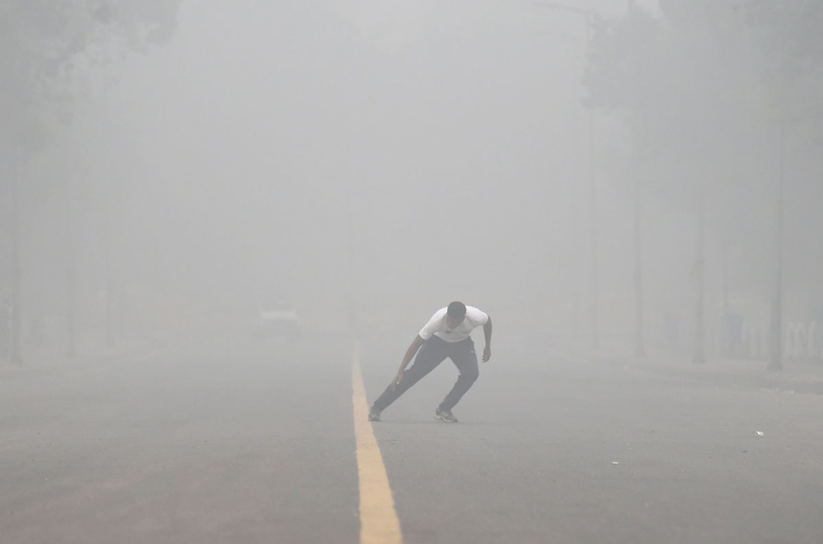 An Indian man does morning exercises on a road as heavy smog covers New Delhi on November 7, 2016. An Indian man does morning exercises on a road as heavy smog covers New Delhi on November 7, 2016.