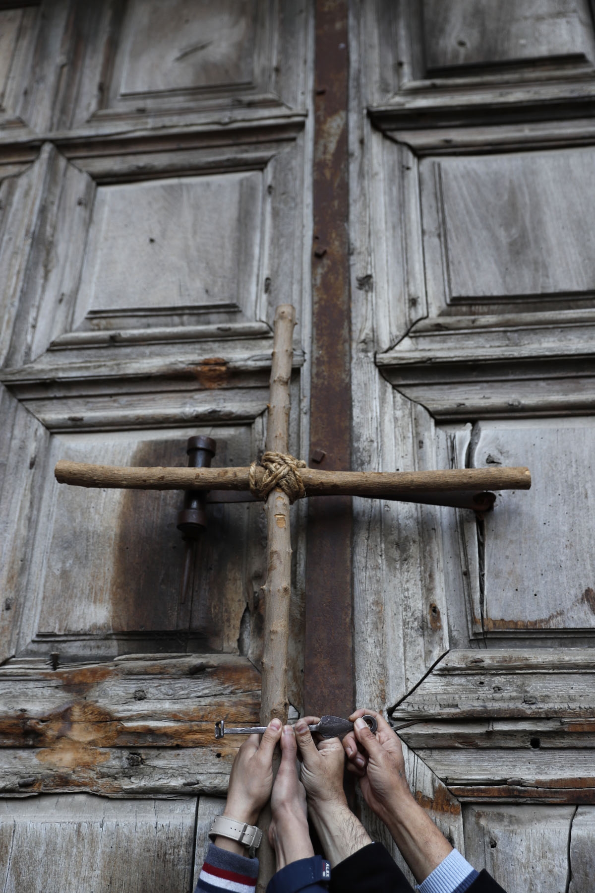Protesters hold a cross during a demonstration outside the closed gate of the Church of the Holy Sepulchre in Jerusalem's Old City on February 27, 2018.