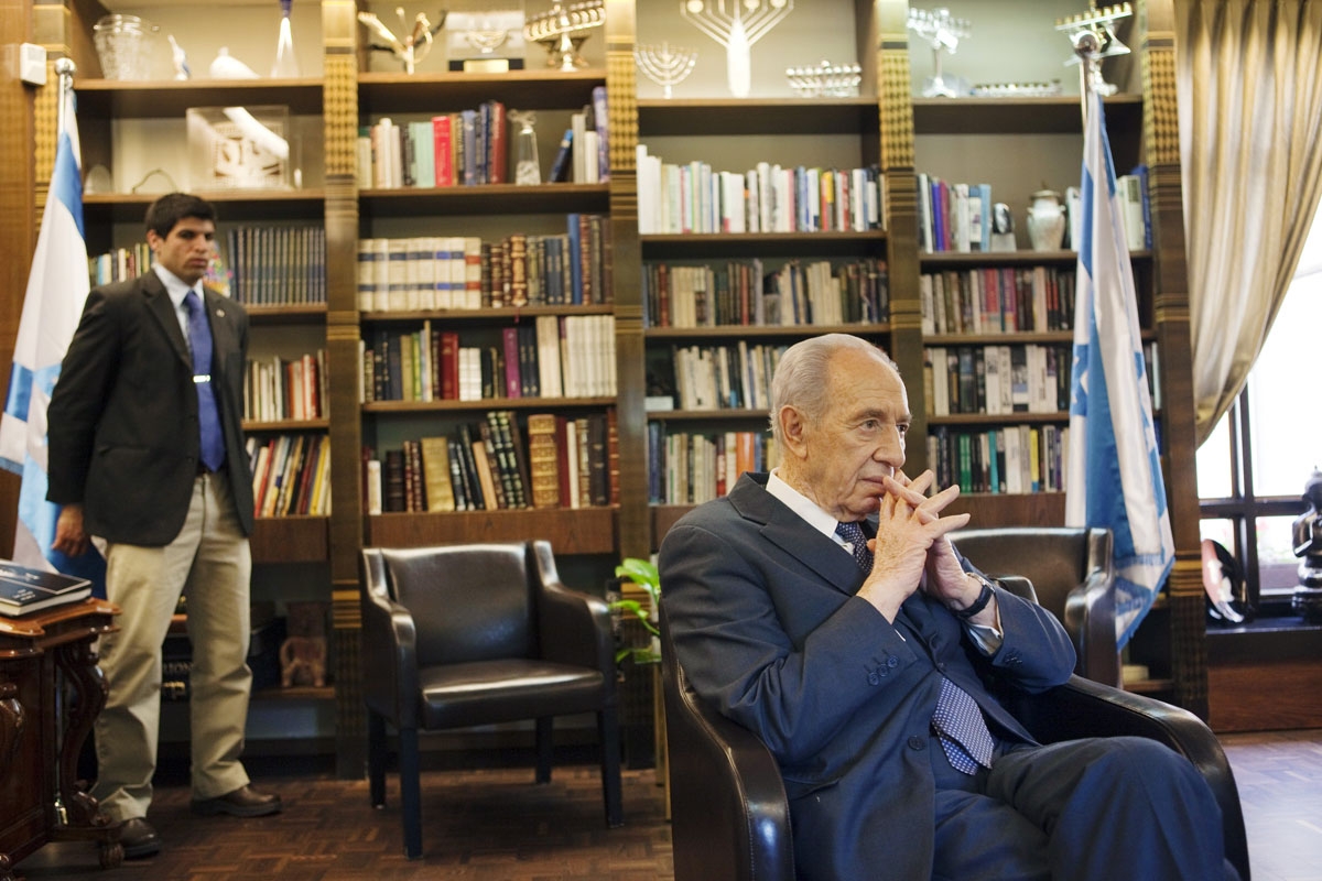Israeli President Shimon Peres answers journalist question during an interview on April 6, 2010 in his residency in Jerusalem while his bodyguard looks on