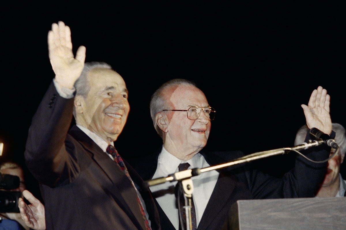 Israeli Prime Minister Yitzhak Rabin (R) and Foreign Minister Shimon Peres wave to a crowd of more than 100,000 Israelis who gathered for a Yes to Peace rally in Tel Aviv on November 4, 1995