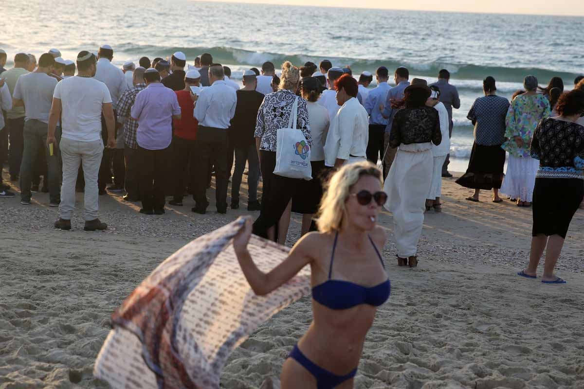 Orthodox Jews (in the background) pray in front of the Mediterranean Sea on October 3 2016 in the Israeli city of Ashdod, south of Tel Aviv, during the Tashlich ritual.