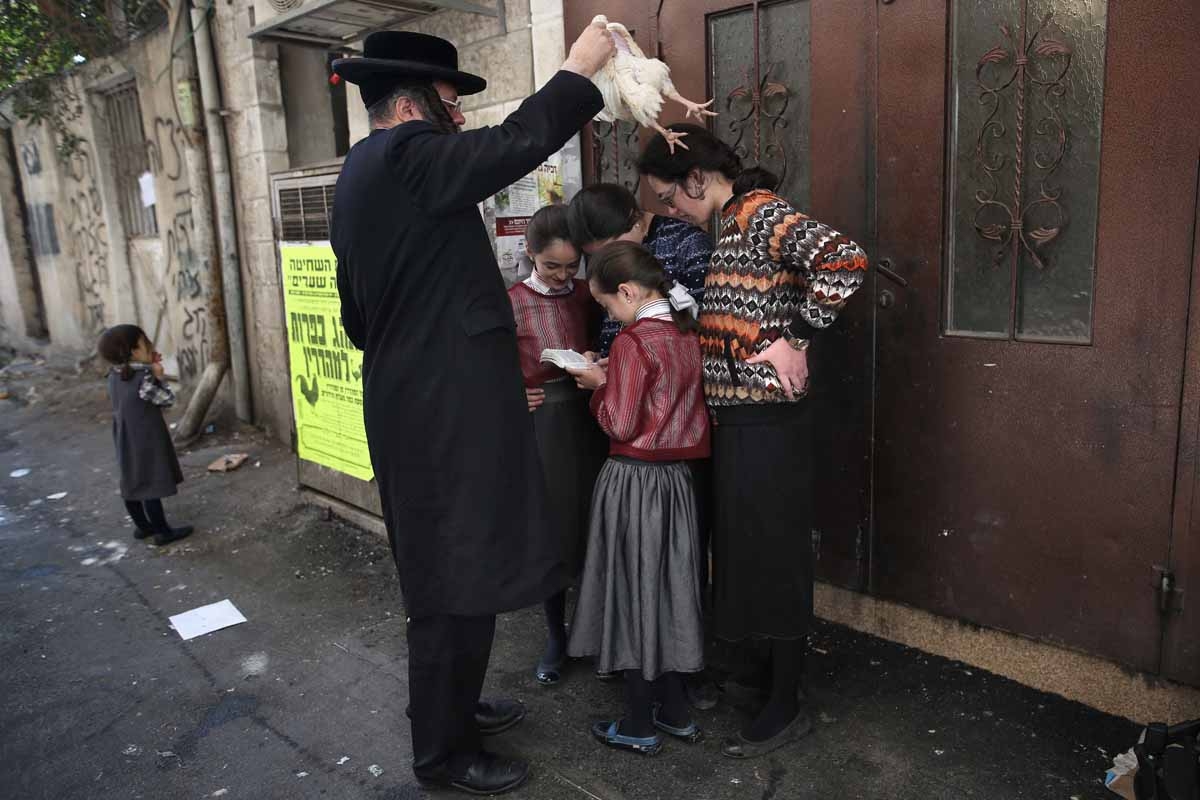 An Ultra-Orthodox Jewish man swings a chicken over his family as they perform the Kapparot ceremony in the ultra-Orthodox neighbourhood of Mea Shearim in Jerusalem on October 10, 2016.