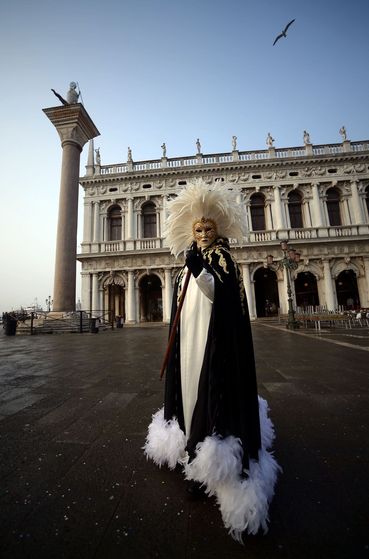 A masked reveller wearing a traditional carnival costume stands in St Mark Square during Venice's Carnival on January 28, 2018.