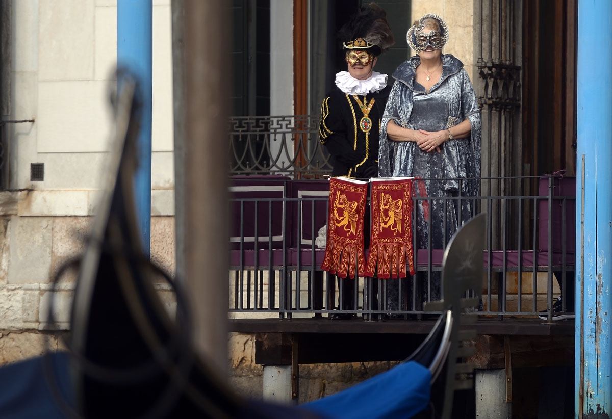 Masked revellers wearing traditional carnival costumes stand near St Mark Square during Venice's Carnival on January 28, 2018.