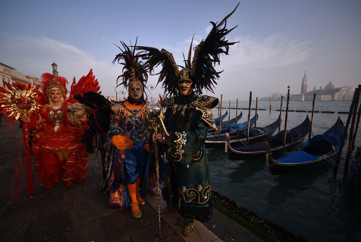 Masked revellers wearing traditional carnival costumes stand in St Mark Square during Venice's Carnival on January 28, 2018.