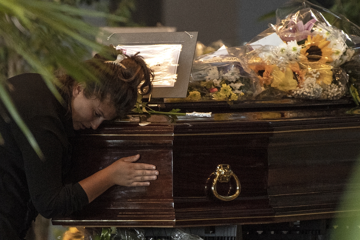 A mourner prays at the coffin of a victim of the Morandi bridge collapse at a funerary home installed at the fairground in Genoa, on August 17, 2018.