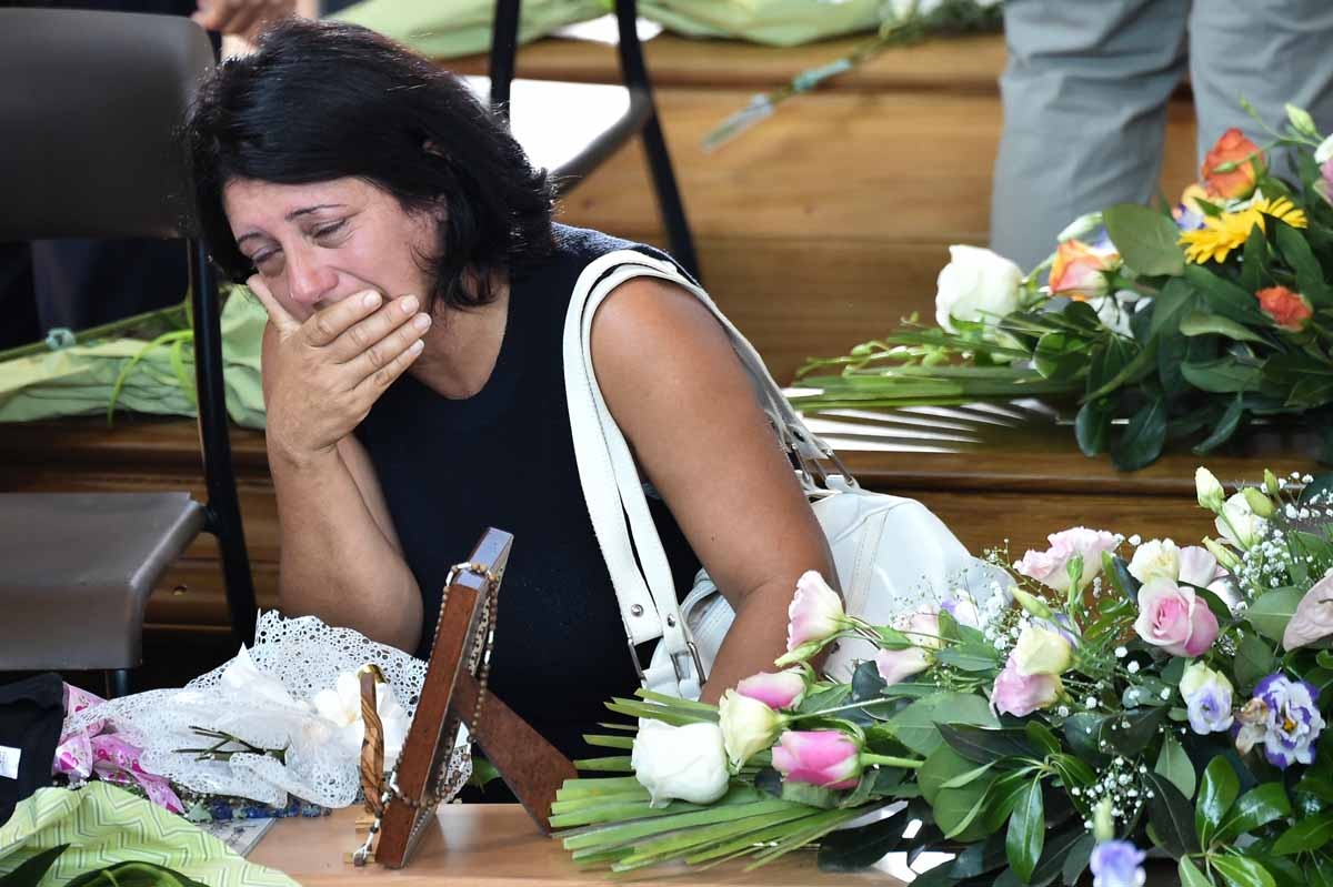 A women mourns next to the coffin of an earthquake victim, in a gymnasium arranged in a chapel of rest on August 27, 2016, in Ascoli Piceno, three days after a 6.2-magnitude earthquake struck the region killing some 281 people.