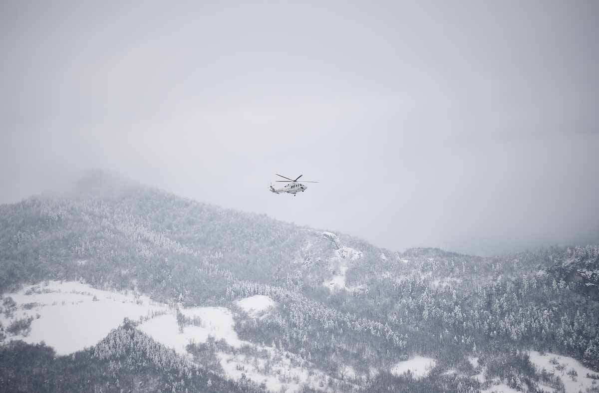 An Italian rescuer helicopter flies towards the site of an avalanche that engulfed the Hotel Rigopiano in earthquake-ravaged central Italy, on January 20, 2017.