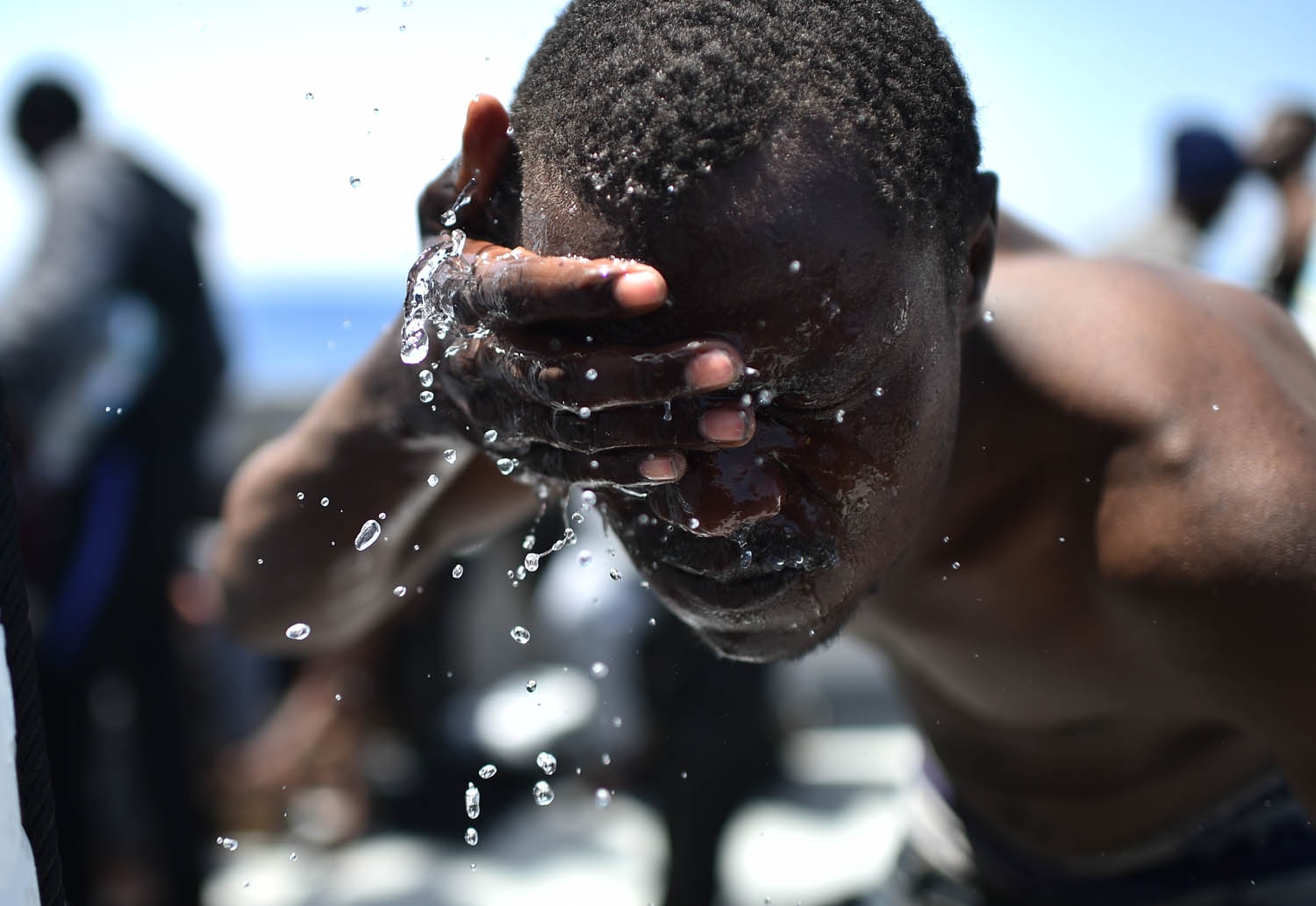 A man sprinkles water onto his face after being rescued during an operation at sea with the Aquarius n May 24, 2016 in the Mediterranean sea in front of the Libyan coas