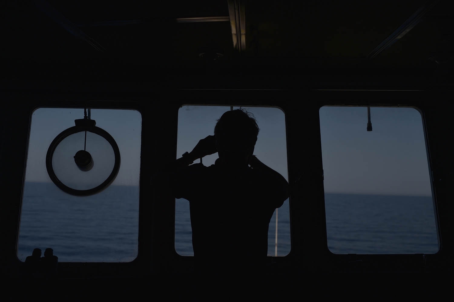 A man watches the sea with binoculars during a rescue operation of migrants and refugees of the Aquarius