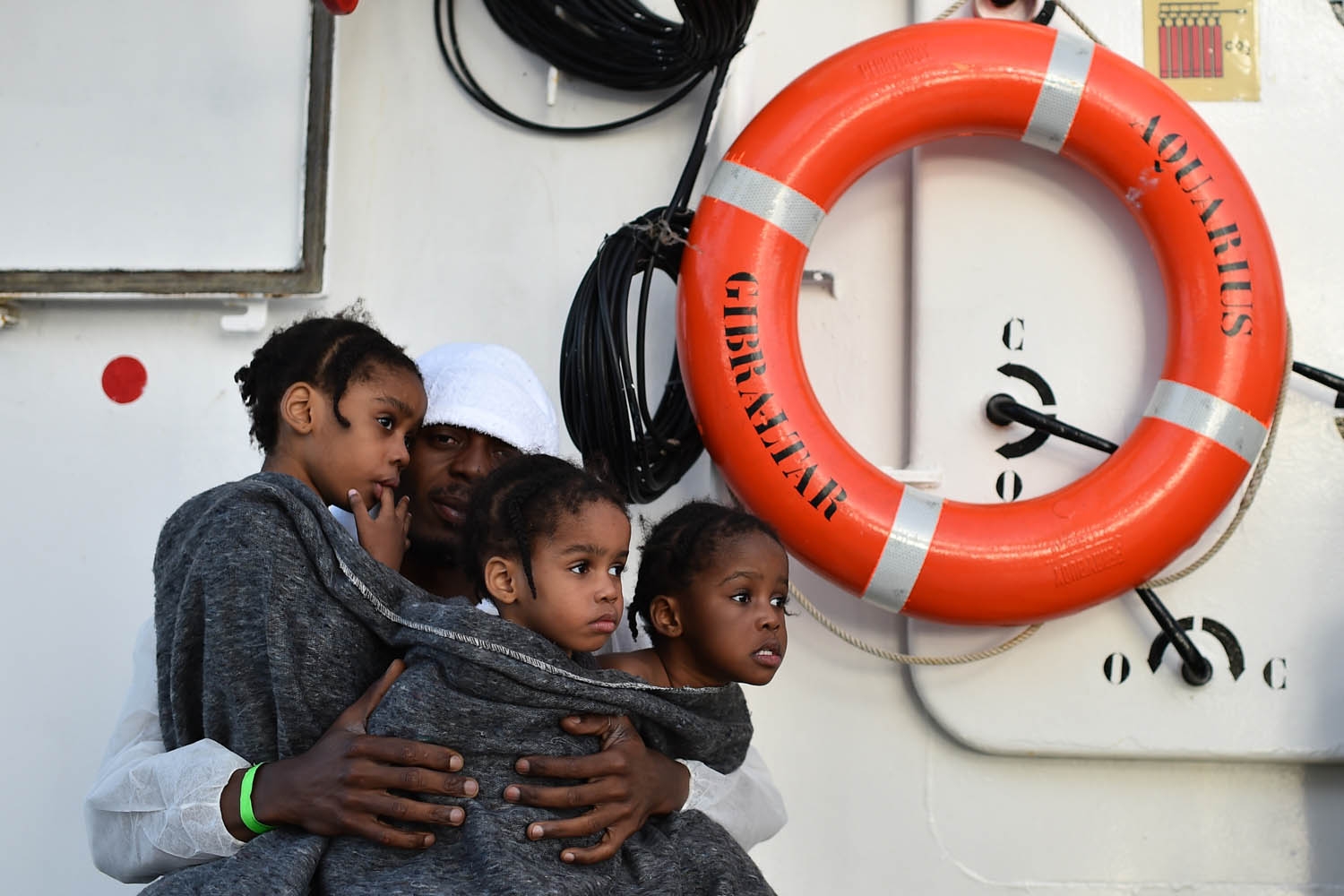 A father holds tight his three daughters aboard the rescue ship Aquarius, on May 24, 2016 after a rescue operation of migrants in front of the Libyan coast