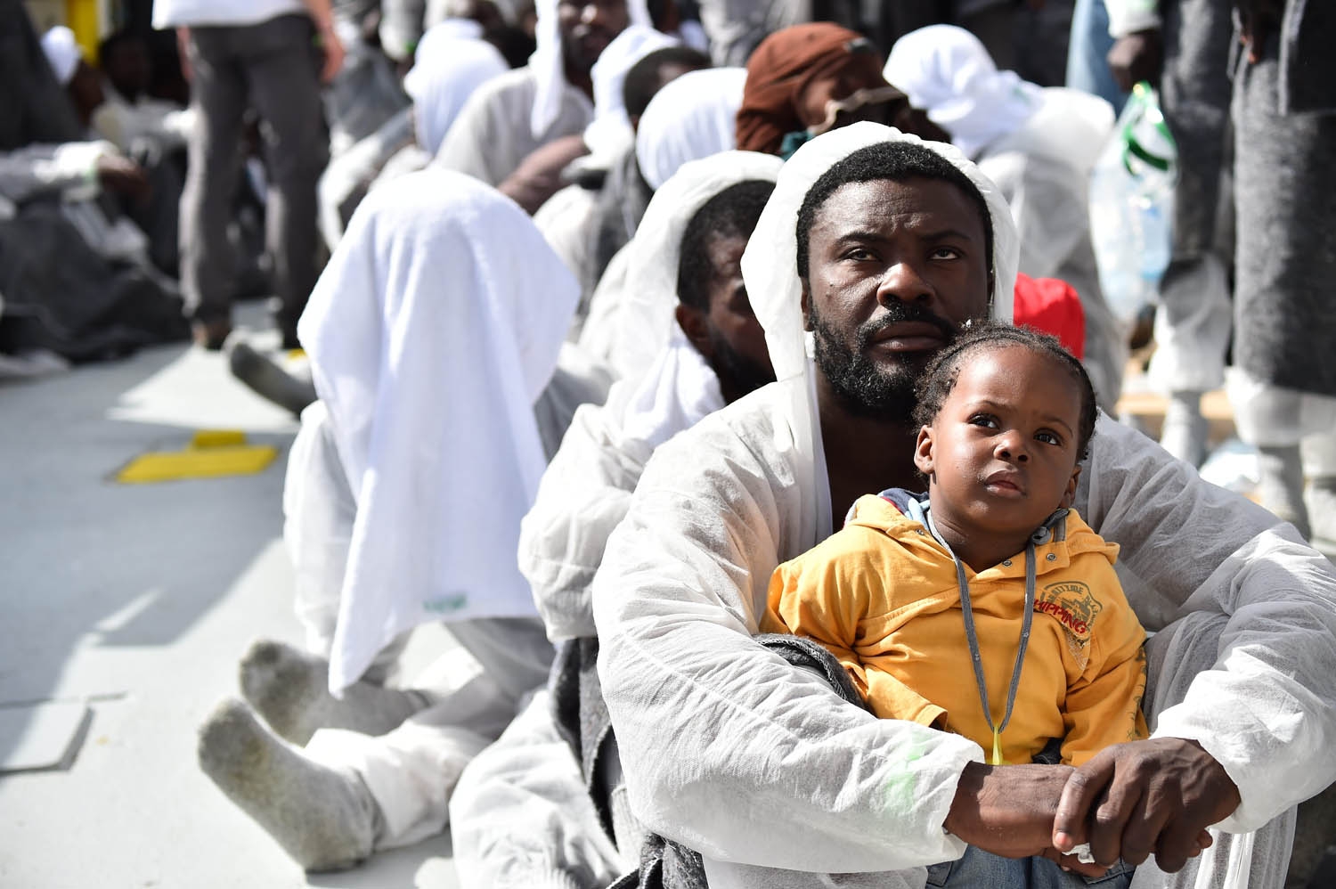 A man and his daughter wait during a distribution of meals aboard the rescue ship Aquarius, on May 25, 2016