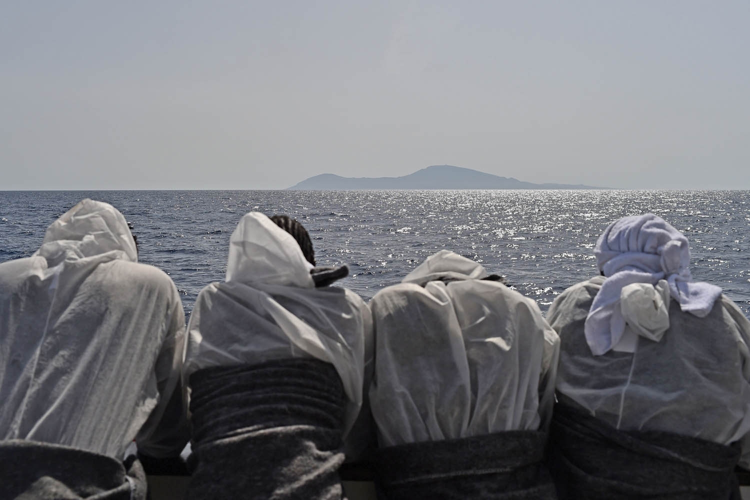 Migrants look at the Pantelleria island from the rescue ship Aquarius, on May 25, 2016