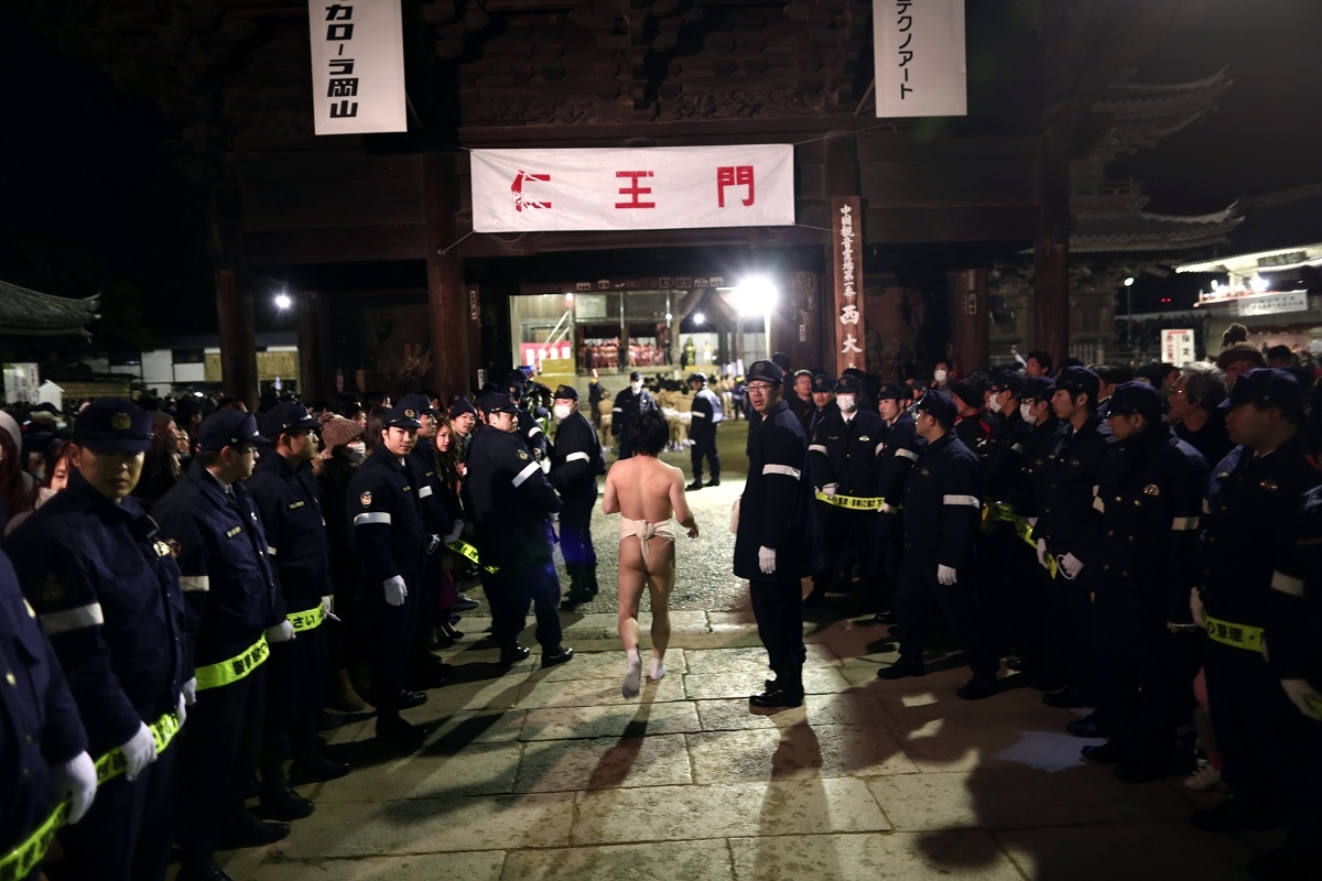 In this picture taken on February 18, 2017, a worshipper runs amid policemen towards Saidaiji Temple to attend the annual Naked Man Festival or 'Hadaka Matsuri' in Okayama, western Japan.With only a skimpy loincloth to protect their modesty, thousands of