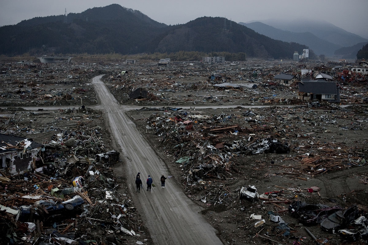 Local residents walk among destroyed houses and debris in the tsunami-damaged city of Rikuzentakata, in Iwate prefecture on March 22, 2011.