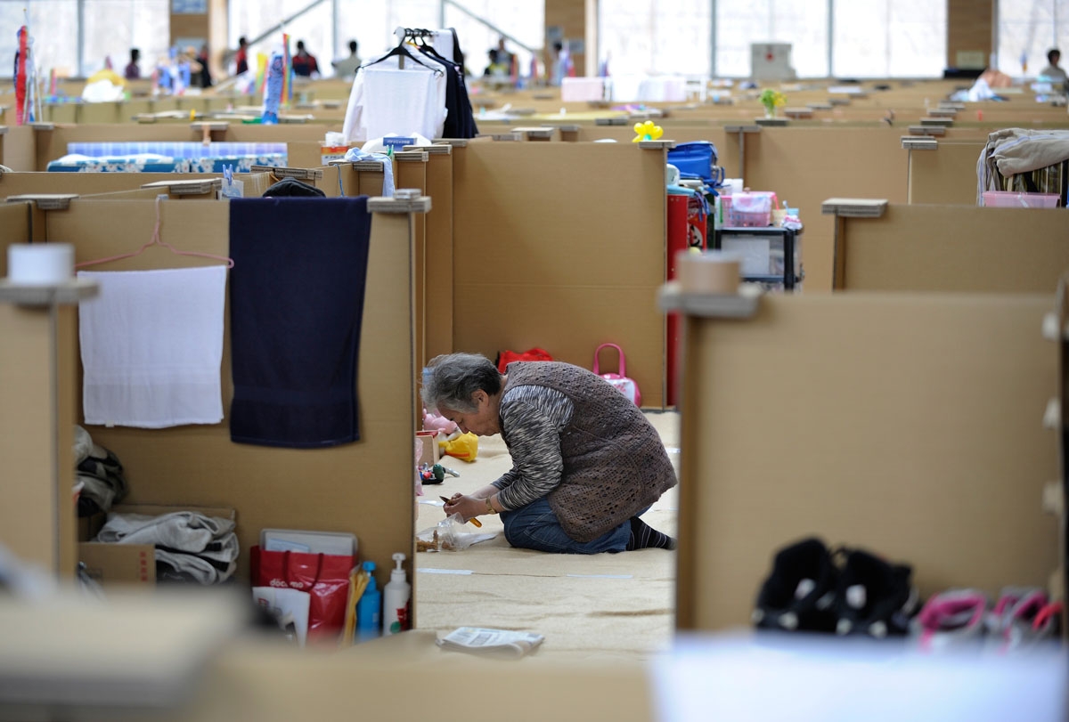 An elderly woman prepares lunch in her little partitioned unit divided by cardboard walls at an evacuation centre for people effected by the March 11 earthquake and tsunami in Miyako