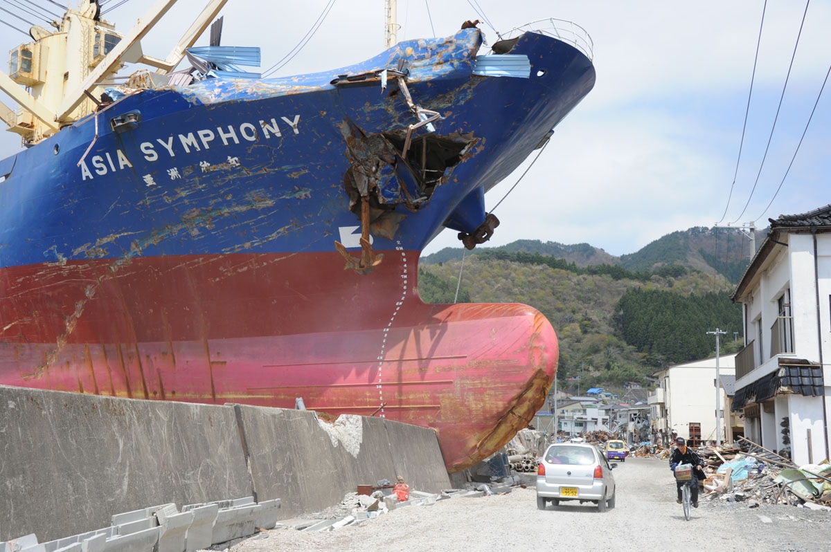 Residents travel on the opened road in front of the 4,724-tonne freighter M.V. Asia Symphony, grounded by the recent tsunami in Kamaishi, Iwate prefecture on May 6, 2011. T