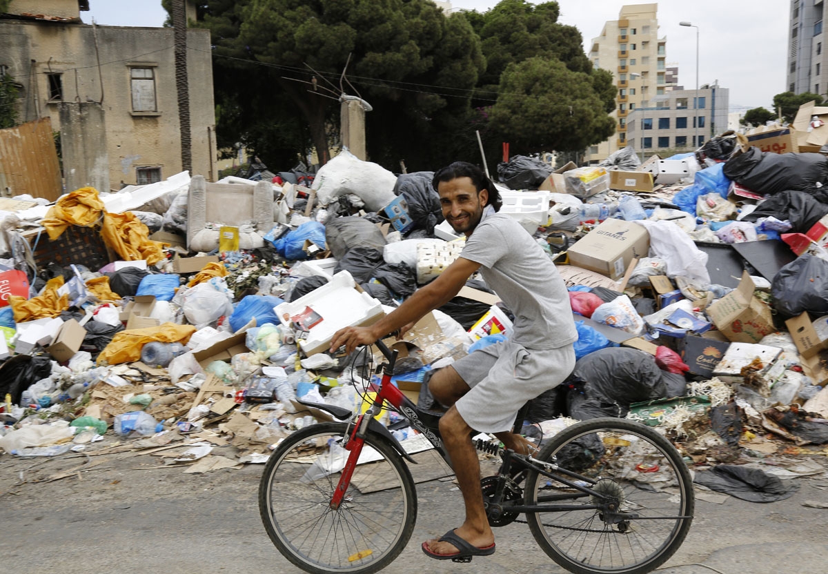 A man rides his bicycle in front of a temporary garbage dump in the neighbourhood Bourj Hammoud, northeast of the Lebanese capital Beirut on September 1, 2016