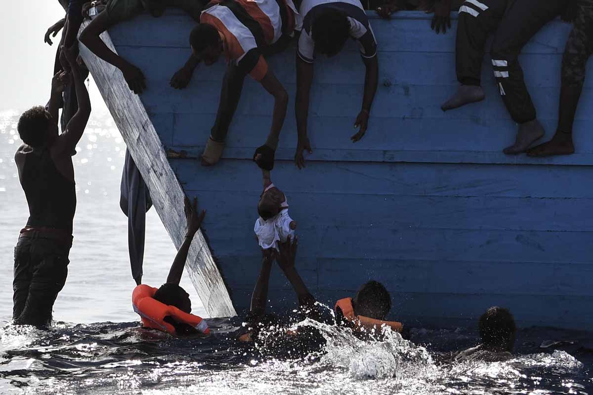 Migrants try to pull a child out of the water as they wait to be rescued by members of Proactiva Open Arms NGO in the Mediterranean sea, some 12 nautical miles north of Libya, on October 4, 2016. Migrants try to pull a child out of the water as they wait to be rescued by members of Proactiva Open Arms NGO in the Mediterranean sea, some 12 nautical miles north of Libya, on October 4, 2016.