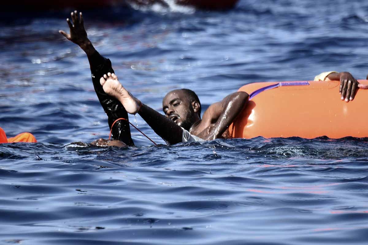 Migrants hold on a flotation tube as they wait to be rescued by members of Proactiva Open Arms NGO in the Mediterranean sea, some 12 nautical miles north of Libya, on October 4, 2016. Migrants hold on a flotation tube as they wait to be rescued by members of Proactiva Open Arms NGO in the Mediterranean sea, some 12 nautical miles north of Libya, on October 4, 2016.