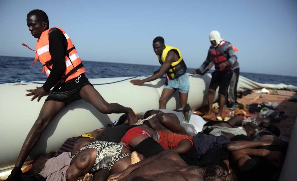 Migrants step over dead bodies while being rescued by members of Proactiva Open Arms NGO in the Mediterranean Sea, some 12 nautical miles north of Libya, on October 4, 2016. Migrants step over dead bodies while being rescued by members of Proactiva Open Arms NGO in the Mediterranean Sea, some 12 nautical miles north of Libya, on October 4, 2016.