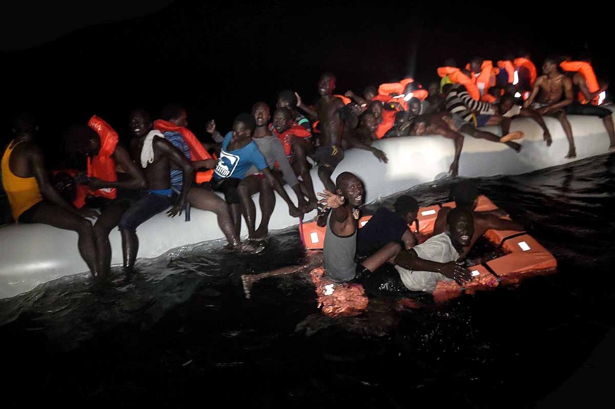 Migrants and refugees wait to be rescued from their sinking rubber boat some eight nautical miles off Libya's Mediterranean coastline on October 12, 2016. Migrants and refugees wait to be rescued from their sinking rubber boat some eight nautical miles off Libya's Mediterranean coastline on October 12, 2016.