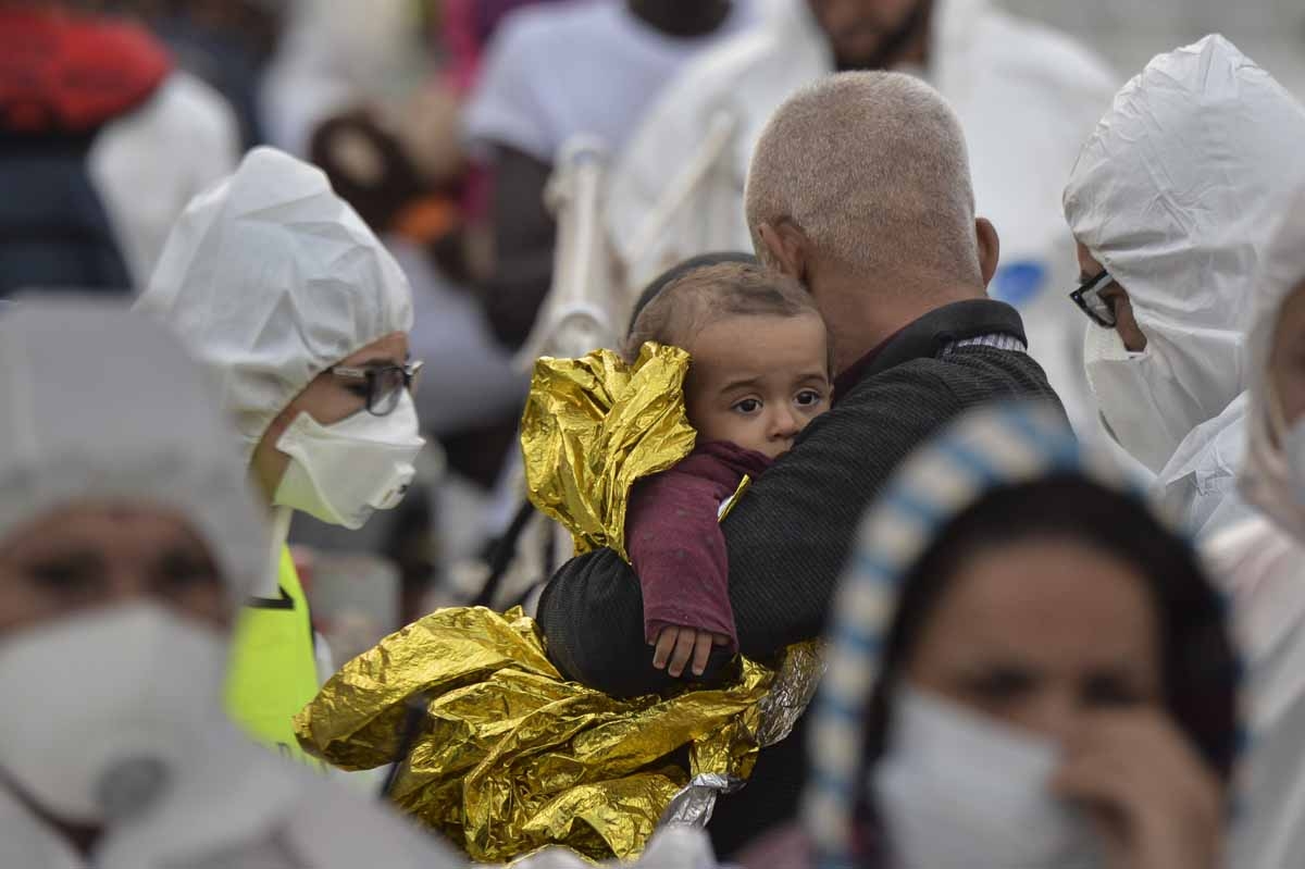 A man holds a baby with a rescue blanket in his arms as a member of the Italian red cross examines them after they disembarked from the Topaz Responder, a rescue ship run by Maltese NGO MOAS, at the Brindisi's harbour on October 27, 2016. A man holds a baby with a rescue blanket in his arms as a member of the Italian red cross examines them after they disembarked from the Topaz Responder, a rescue ship run by Maltese NGO MOAS, at the Brindisi's harbour on October 27, 2016.