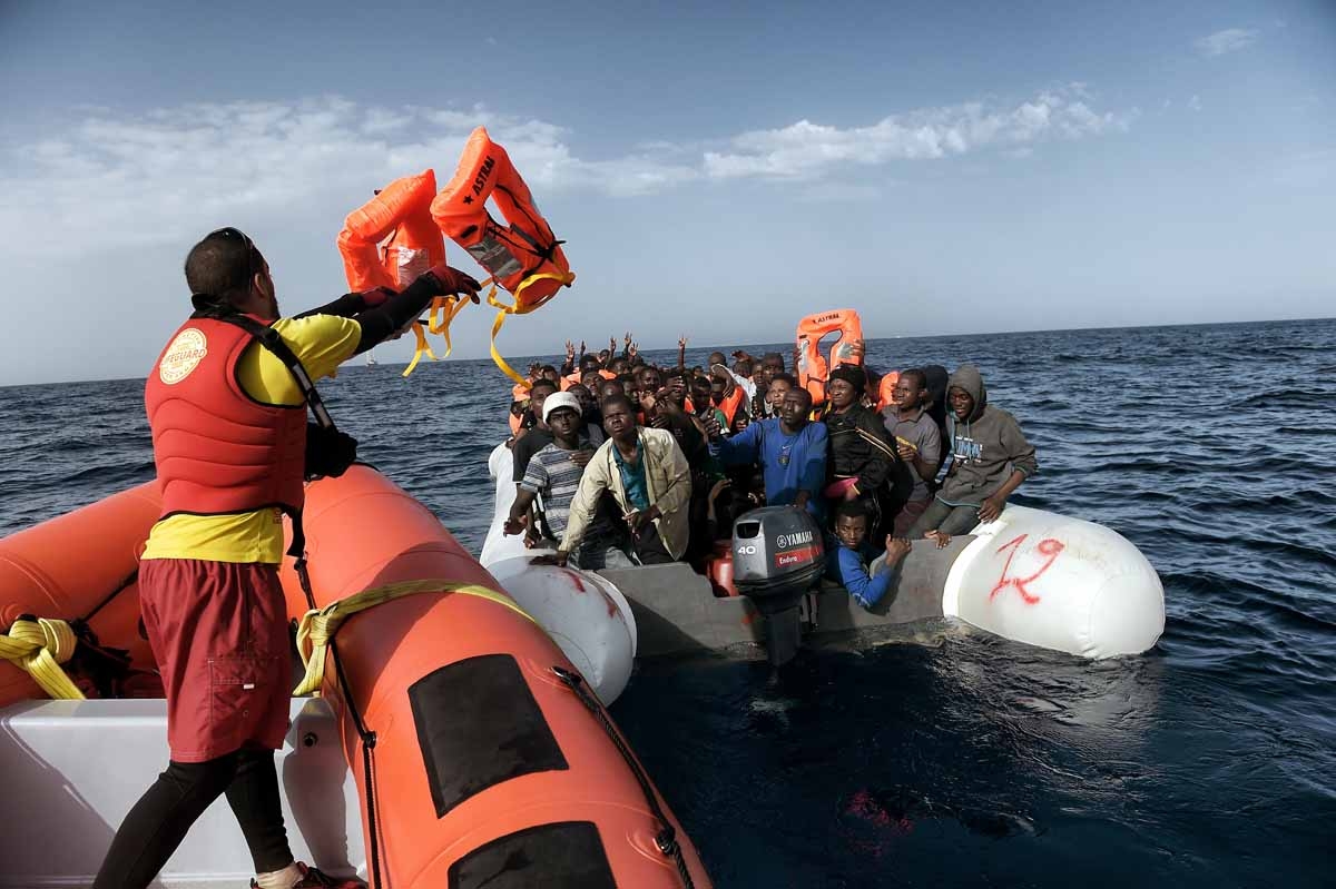A member of Spanish humanitarian NGO Proactiva Open Arms, throws life jackets to refugees and migrants during a rescue operation off the coast of Libya on October 3, 2016. A member of Spanish humanitarian NGO Proactiva Open Arms, throws life jackets to refugees and migrants during a rescue operation off the coast of Libya on October 3, 2016.