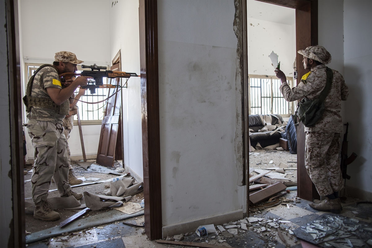 A fighter loyal to Libya's Government of National Accord aims his weapon towards Islamic State (IS) group positions in District 3 while his comrade uses a broken mirror to observe their movement on the western frontline in Sirte on October 2, 2016.
