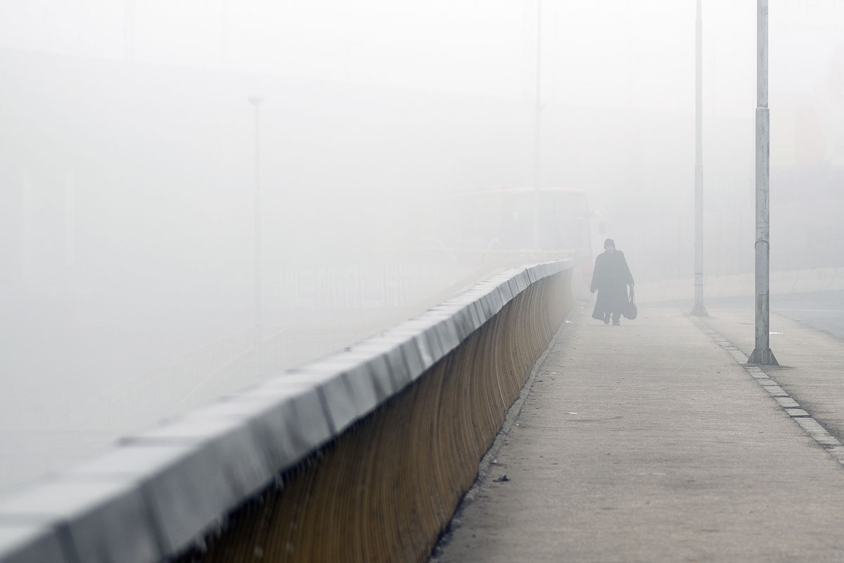A person walks on a bridge through dense fog in Skopje on December 24, 2015.