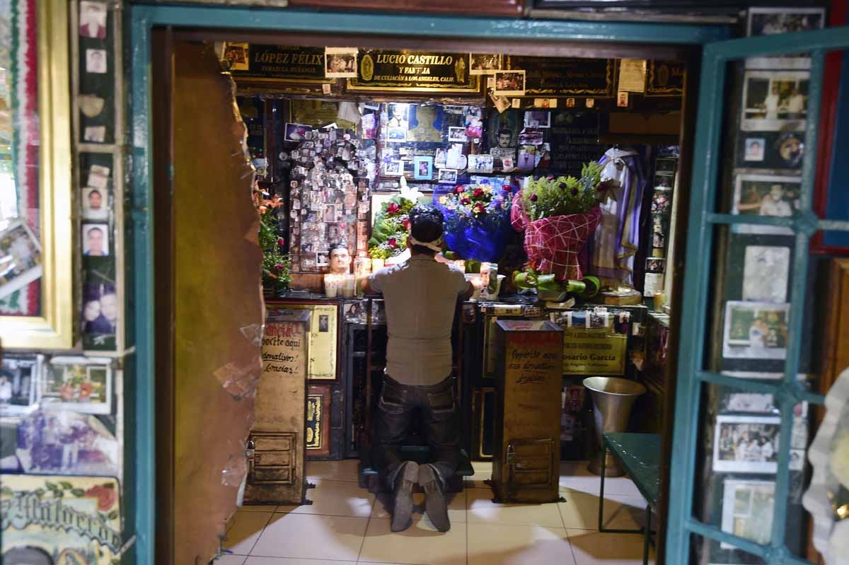 A man prays at the Malverde chapel -devoted to narco-saint Jesus Malverde, who according to legend was a Robin Hood-type bandit who stole from the rich and gave to the poor- in Culiacan, Sinaloa state in northwest Mexico, on December 7, 2016.