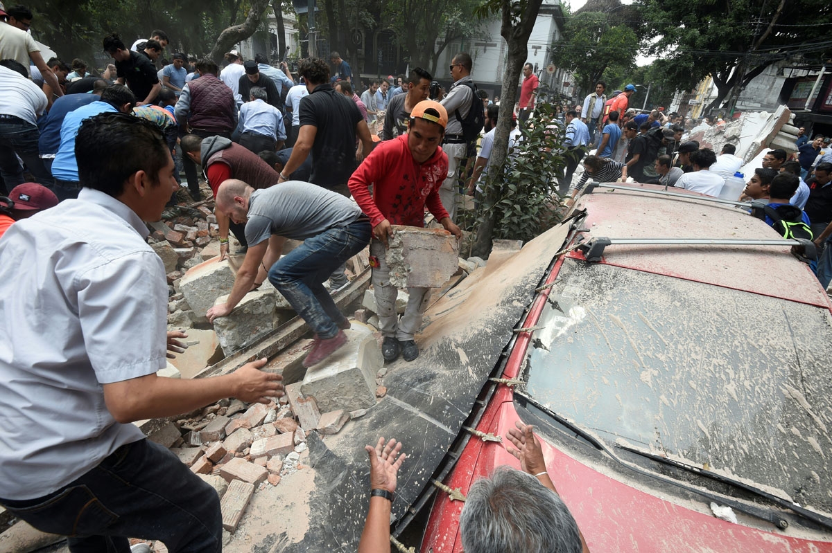People remove debris of a building which collapsed after a quake rattled Mexico City on September 19, 2017.