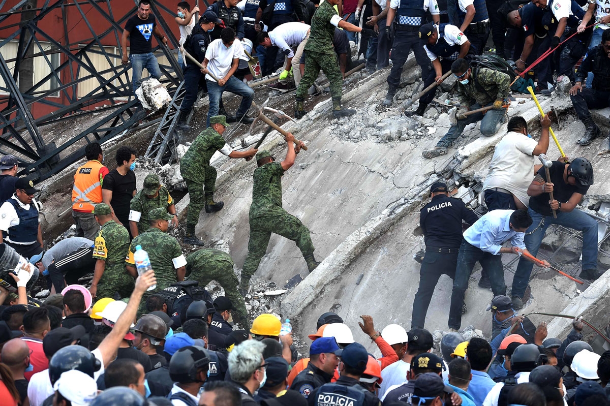 Rescuers, firefighters, policemen, soldiers and volunteers remove rubble and debris from a flattened building in search of survivors after a powerful quake in Mexico City on September 19, 2017.