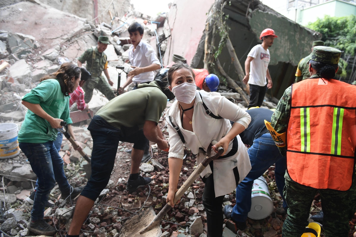 Rescuers, firefighters, policemen, soldiers and volunteers remove rubble and debris from a flattened building in search of survivors after a powerful quake in Mexico City on September 19, 2017.