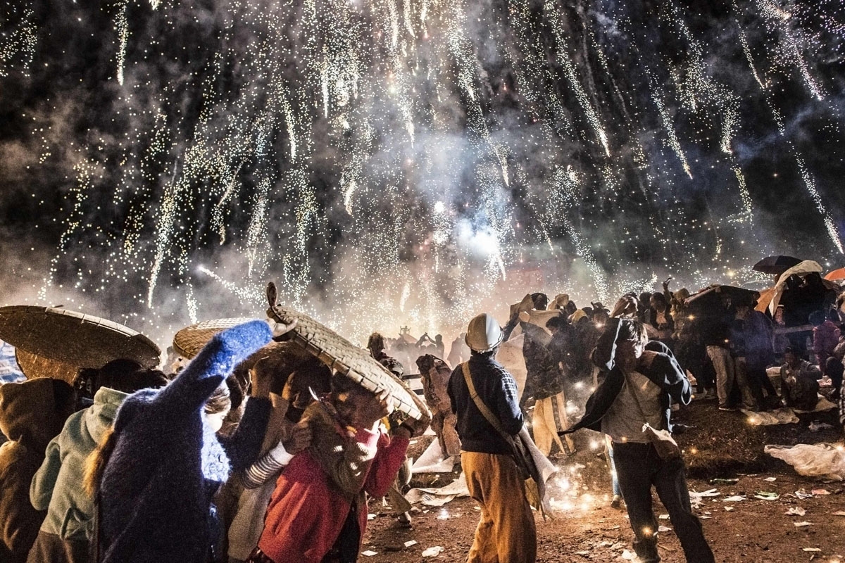 This picture taken on November 12, 2016 shows people protecting themselves from fireworks, being carried by a hot air balloon, that ignited before the balloon was at a sufficient height during the Tazaungdaing Lighting Festival at Taunggyi in Myanmar's no