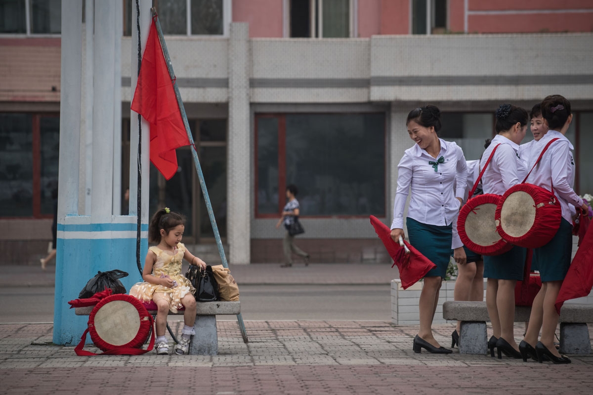 A child waits as members of a local propaganda troupe prepare to perform in a public square as part of a 200 day campaign aimed at kickstarting a new economic plan, in Pyongyang on July 10, 2016