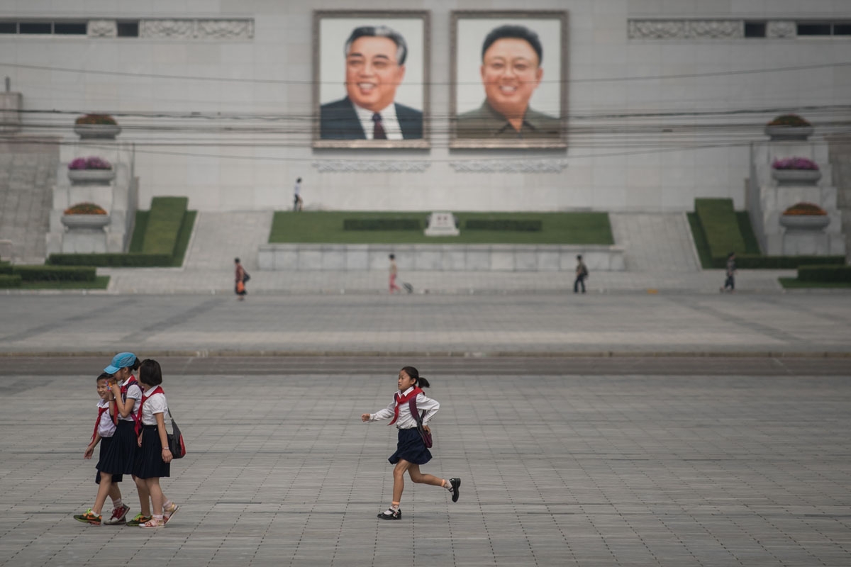 In a photo taken on July 9, 2016 a child runs before the portraits of former North Korean leaders Kim Il-Sung (L) and Kim Jong-Il (R), in Pyongyang