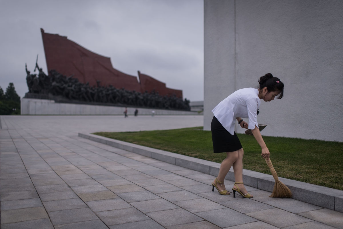 A Pyongyang resident undertakes volunteer work as she sweeps around statues on Mansu hill in Pyongyang on July 13, 2016