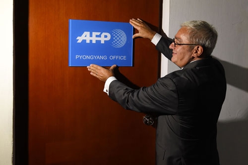 In this picture taken on September 6, 2016, Chief Executive and Chairman of Agence France-Presse Emmanuel Hoog hangs a company sign on the door of the news agency's bureau in Pyongyang