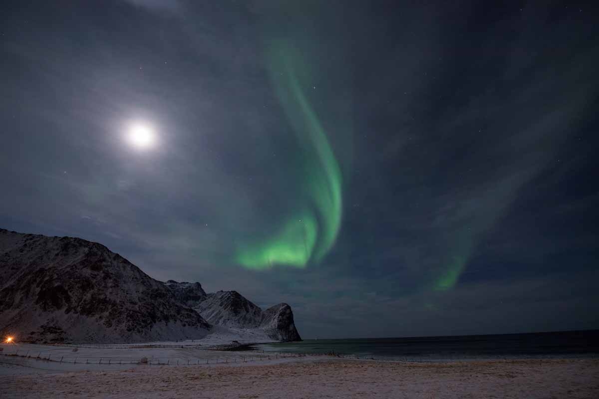 The Northern Lights, also known as 'Aurora borealis' flash across the sky above Unstad, a town know for being the world's most northern artic surf school on March 7, 2017. / AFP PHOTO / OLIVIER MORIN