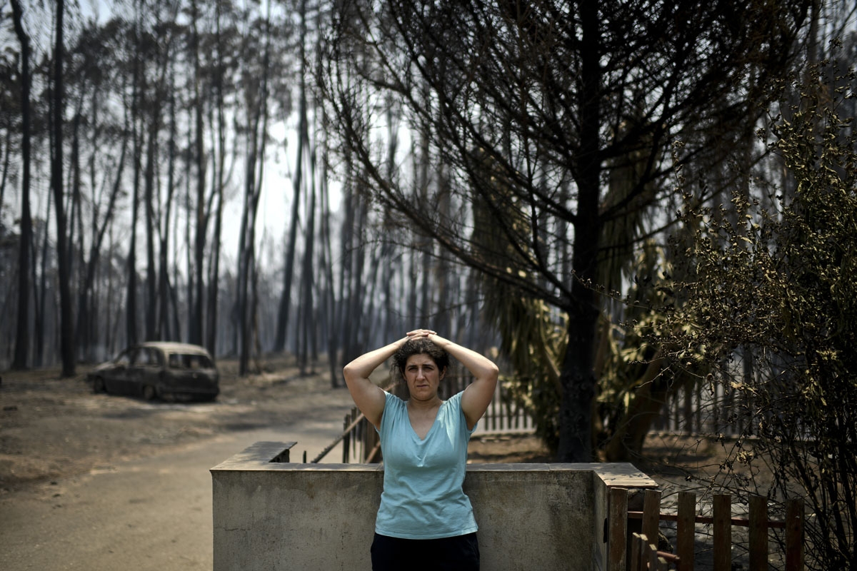 Anabela Silva stands in front of her house with her burnt car in the background after a wildfire in Figueiro dos Vinhos on June 18, 2017.