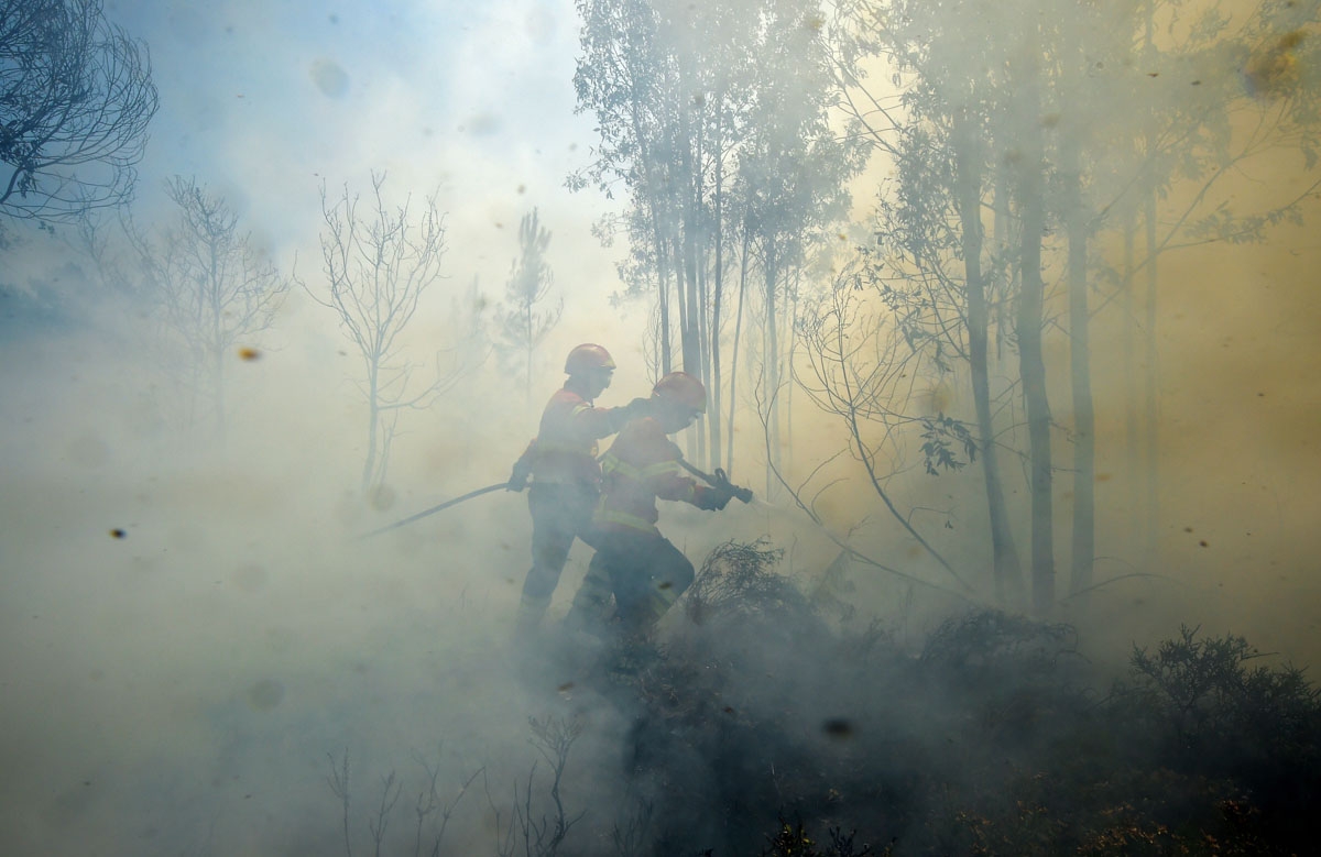 Firefighters use a hose to combat a wildfire in Vale da Ponte, Pedrograo Grande, on June 20, 2017.