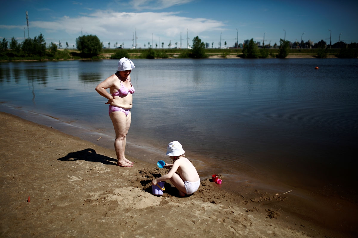 A woman looks after a girl on a beach by the Volga river in Kazan on June 17, 2018 during the Russia 2018 World Cup football tournament.