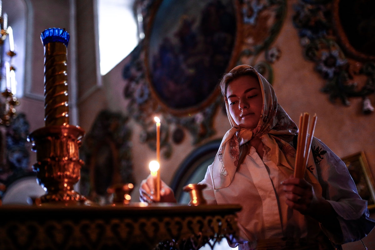 A woman lights a candle in the Saint Peter and Saint Paul church in Kazan on June 18, 2018, during the Russia 2018 World Cup football tournament. / AFP PHOTO / Benjamin CREMEL