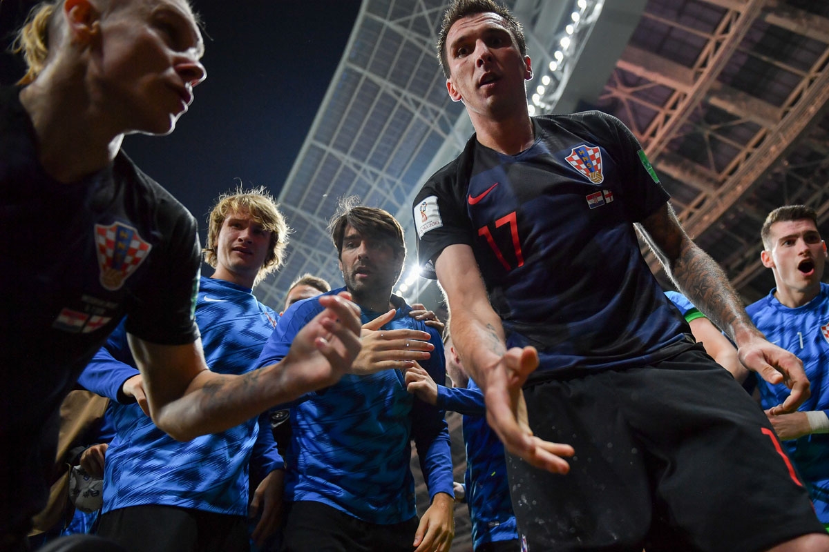 Croatia's forward Mario Mandzukic (C) offers to help AFP photographer Yuri Cortez after he fell on him with teammates while celebrating their second goal during the Russia 2018 World Cup semi-final football match between Croatia and England at the Luzhnik